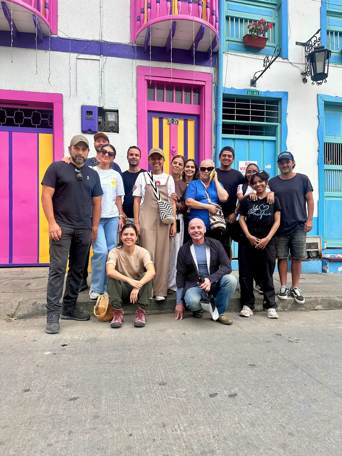 Un grupo de personas frente a las fachadas de colores de una calle del Eje Cafetero.