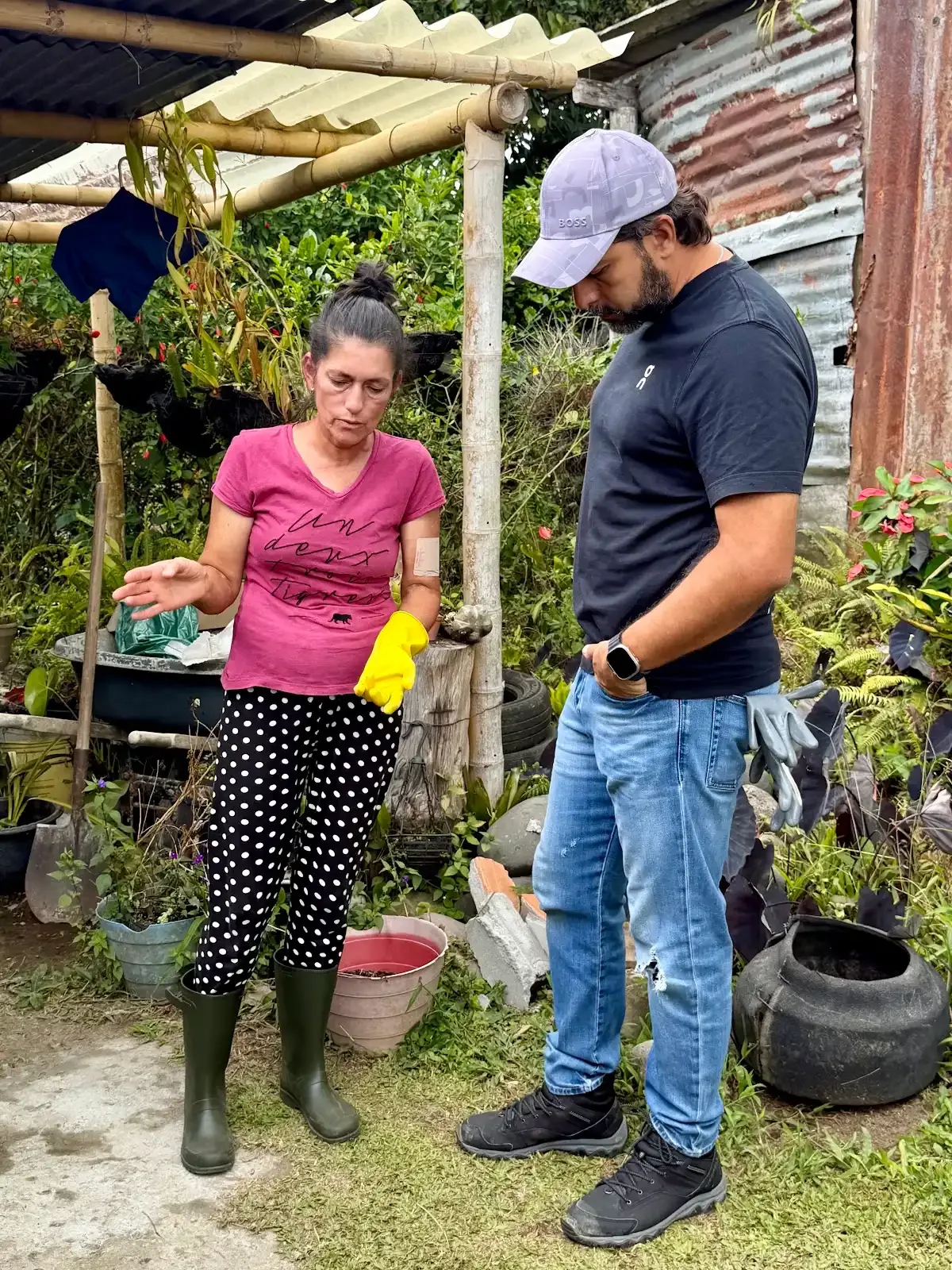 Una mujer con guantes de trabajo y un hombre conversan junto a una estructura de guadua.